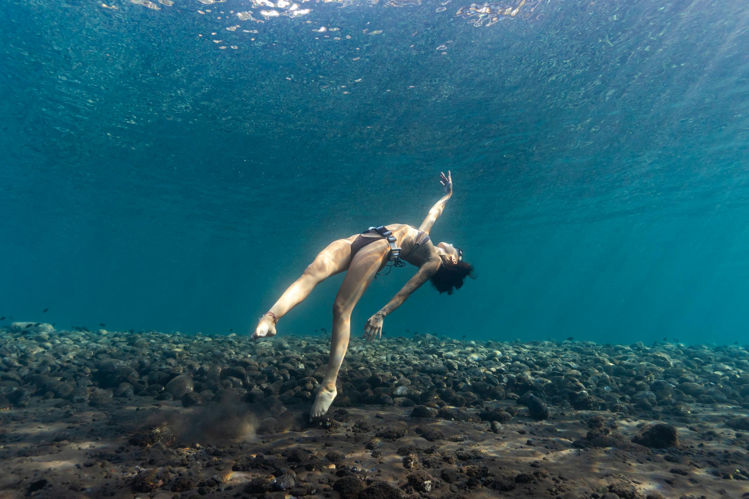 A woman gracefully diving underwater showcasing the serene aquatic environment.