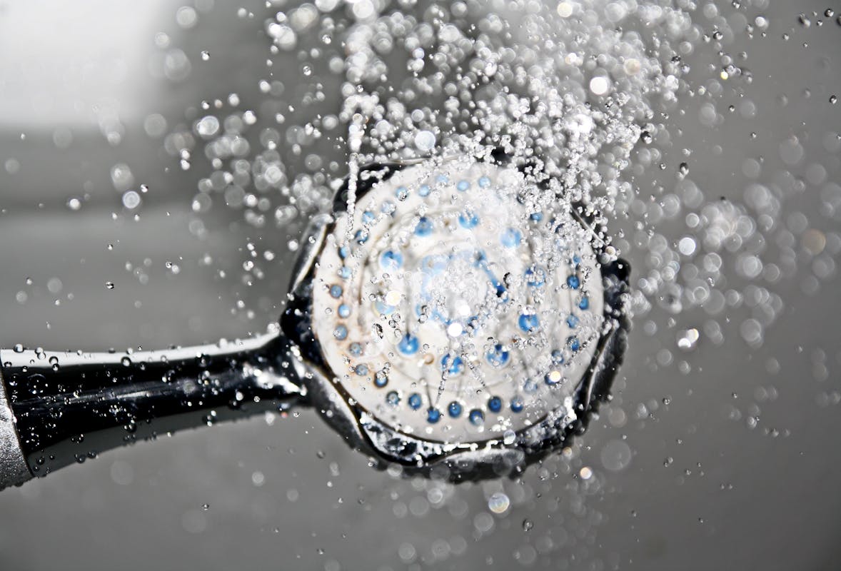 Close-up of a shower head releasing cold water droplets, creating a crisp and refreshing bathroom scene.